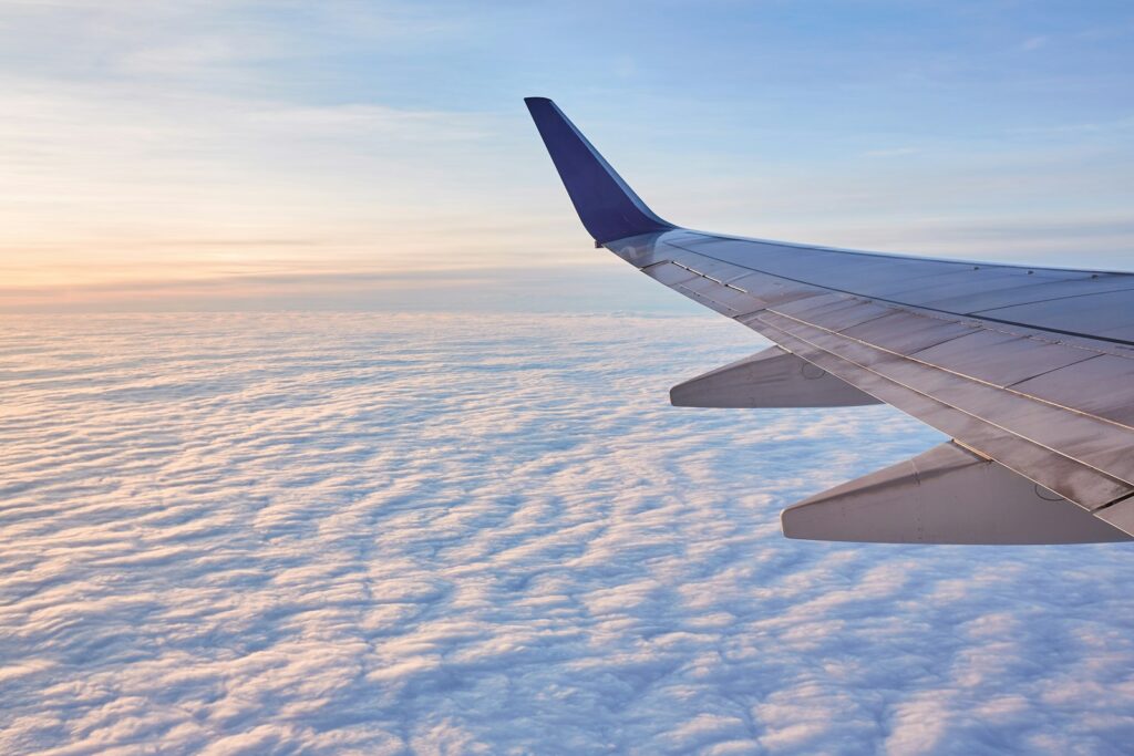 雲の上を飛ぶ飛行機の翼（日本からの出国のイメージ）