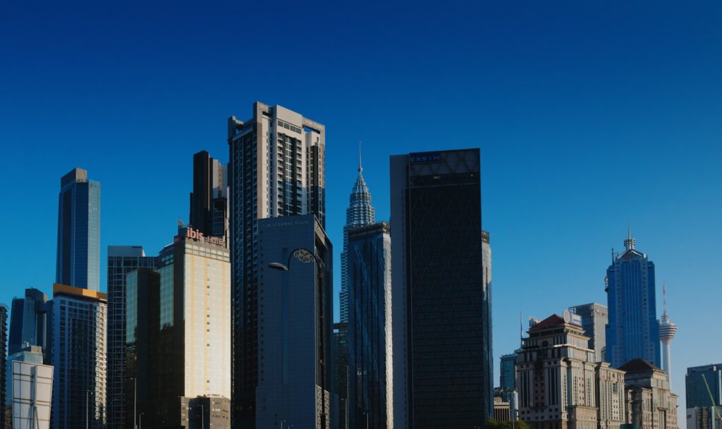 青空の下のクアラルンプールの高層ビル群(マレーシアで働くイメージ)